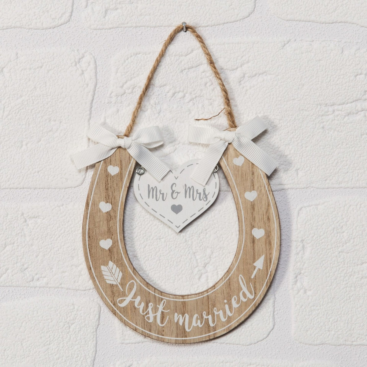 Horseshoe-shaped light wood MDF wall art featuring Just Married lettering, white hearts, an arrow motif, a hanging Mr & Mrs heart tag, and white ribbon bows on a jute hanger.