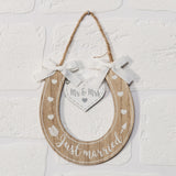 Horseshoe-shaped light wood MDF wall art featuring Just Married lettering, white hearts, an arrow motif, a hanging Mr & Mrs heart tag, and white ribbon bows on a jute hanger.