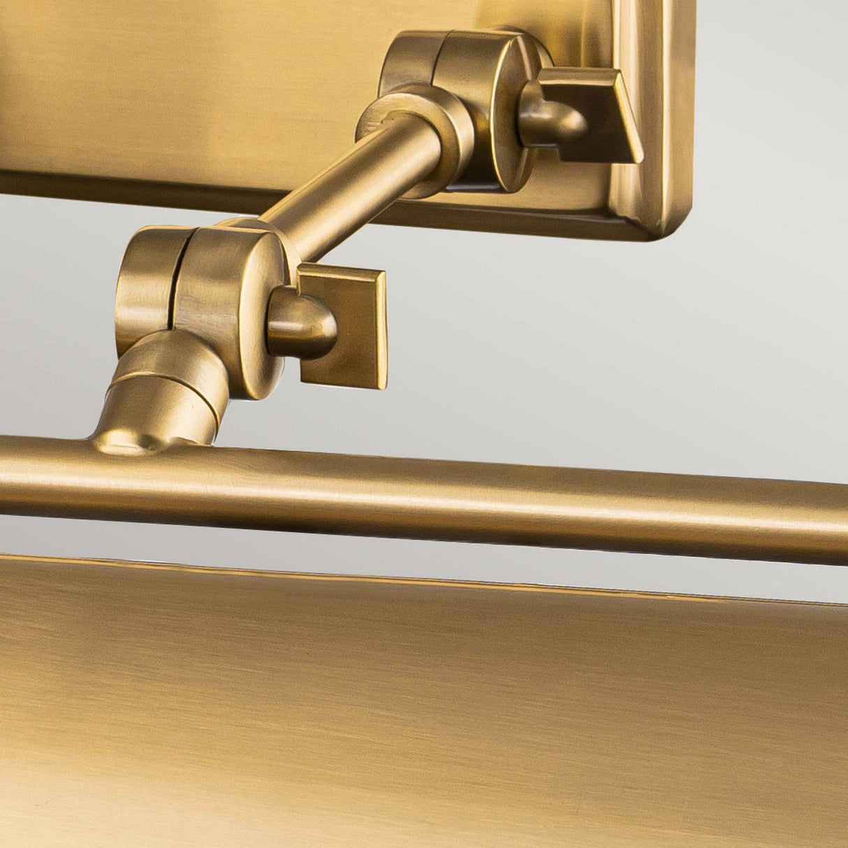 Detailed view of the Winchfield 4 Light Large Picture Light in aged brass, showcasing a rectangular backplate and cylindrical shade. This elegant picture light includes two joints for versatile positioning, set against a neutral background.