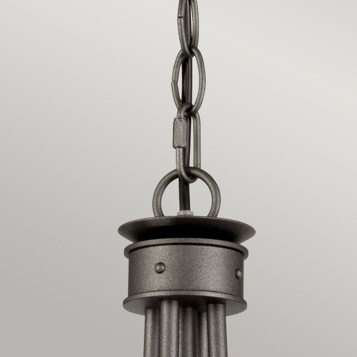 Close-up of the Windsor 4 Light Chandelier - Graphite, showcasing a metal pendant light fixture with a chain link design and hand-crafted detailing. The fixture features a cylindrical base and decorative top in a sleek graphite finish, resembling a chandelier, hanging elegantly against a neutral background.