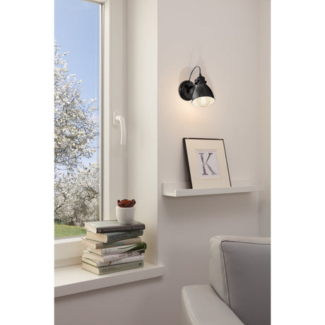 Wirnorne wall light with black dome shade and white interior, mounted beside a window shelf in a living room setting.