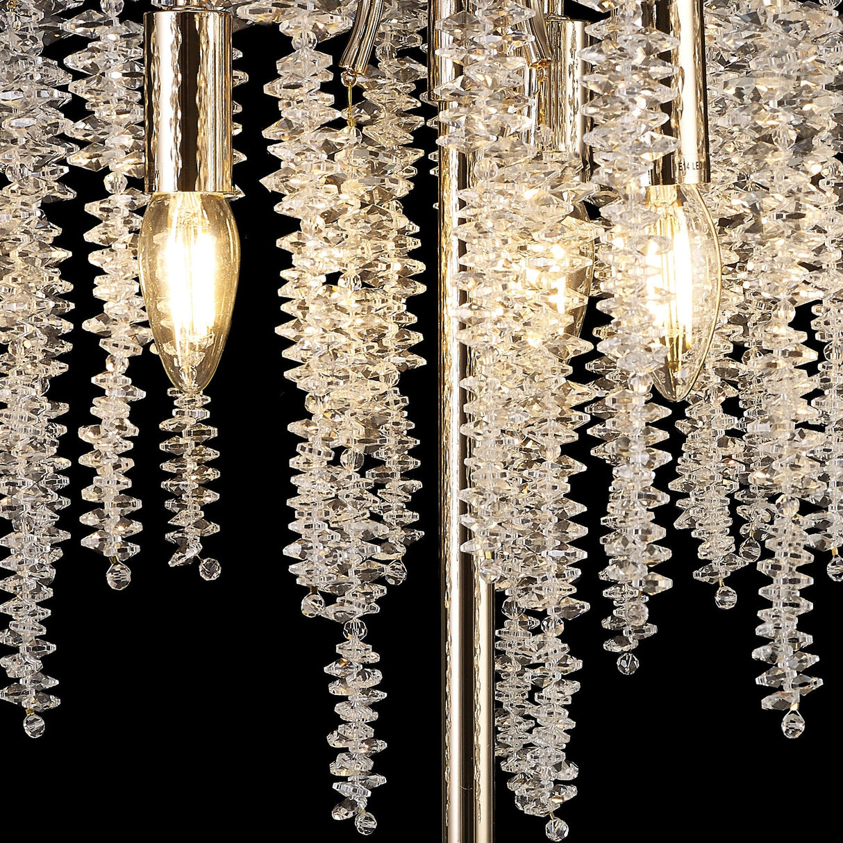 Close-up of the Wisteria 3 Light Table Lamp in gold, featuring clear crystal clusters beside glowing, dimmable bulbs. Set against a black background, the crystals reflect light to create a stunning shimmering effect.