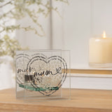 Square clear glass tealight candle holder with double panels, featuring a heart of tiny white hearts, "mum" in black script, and a surrounding ring of words, shown lit on a wooden surface.