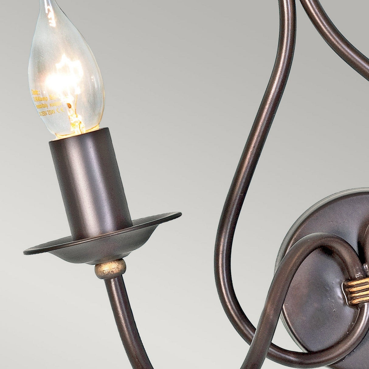 A detailed view of the Windermere 2 Light Wall Light showcases its vintage style, featuring a curved metal arm and exposed bulbs. Handcrafted in the UK, this fixture exudes rustic charm with its dark brown, slightly reflective finish. Mounted on a circular base, it stands out beautifully against the plain light gray background.