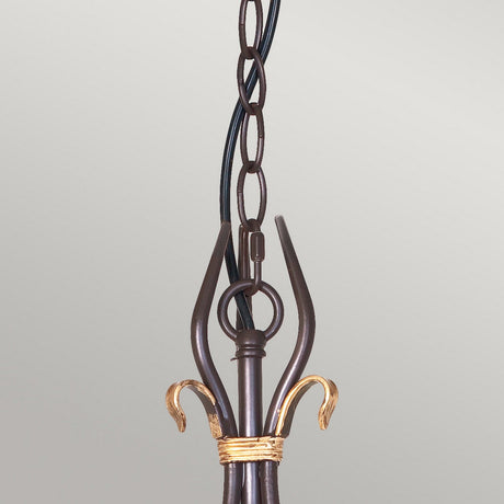 Close-up of the Windermere 3 Light Chandelier in a rustic and gold finish, showcasing its traditional design with curved golden accents and an attached looped chain, set against a plain background.