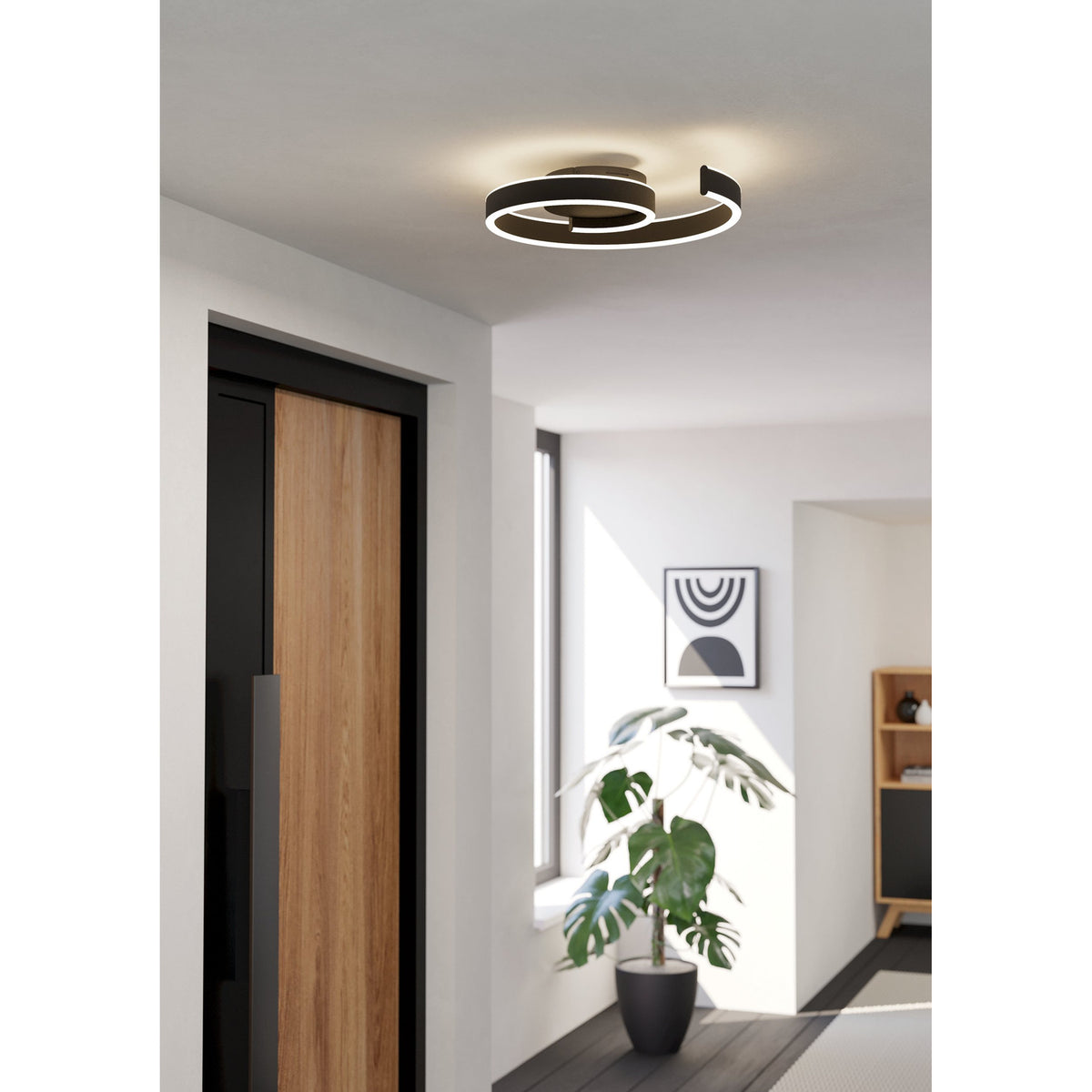 Andabaia Smart LED Flush Ceiling Light in black, a spiral aluminium and steel design with white diffuser, shown illuminated on a hallway ceiling above a wooden door.