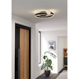 Andabaia Smart LED Flush Ceiling Light in black, a spiral aluminium and steel design with white diffuser, shown illuminated on a hallway ceiling above a wooden door.