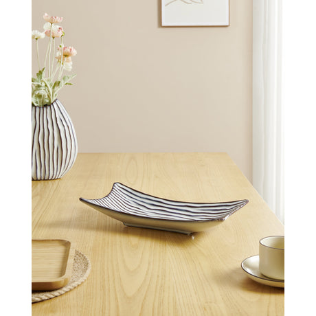 Wormiston ceramic decorative bowl in white with brown wavy ridge pattern, elongated curved tray shape, shown on a wooden table beside a striped vase and teacup.