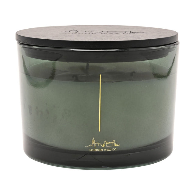 Round three-wick scented candle, 397g, in a smoky green glass vessel with black lid, gold skyline line art, on a plain white background.