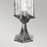 The Wexford 1 Light Pedestal Light - Black/Silver is a vintage-style lantern with geometric patterned glass and a hexagonal metal base, ideal for outdoor lighting, shown against a light gray background.