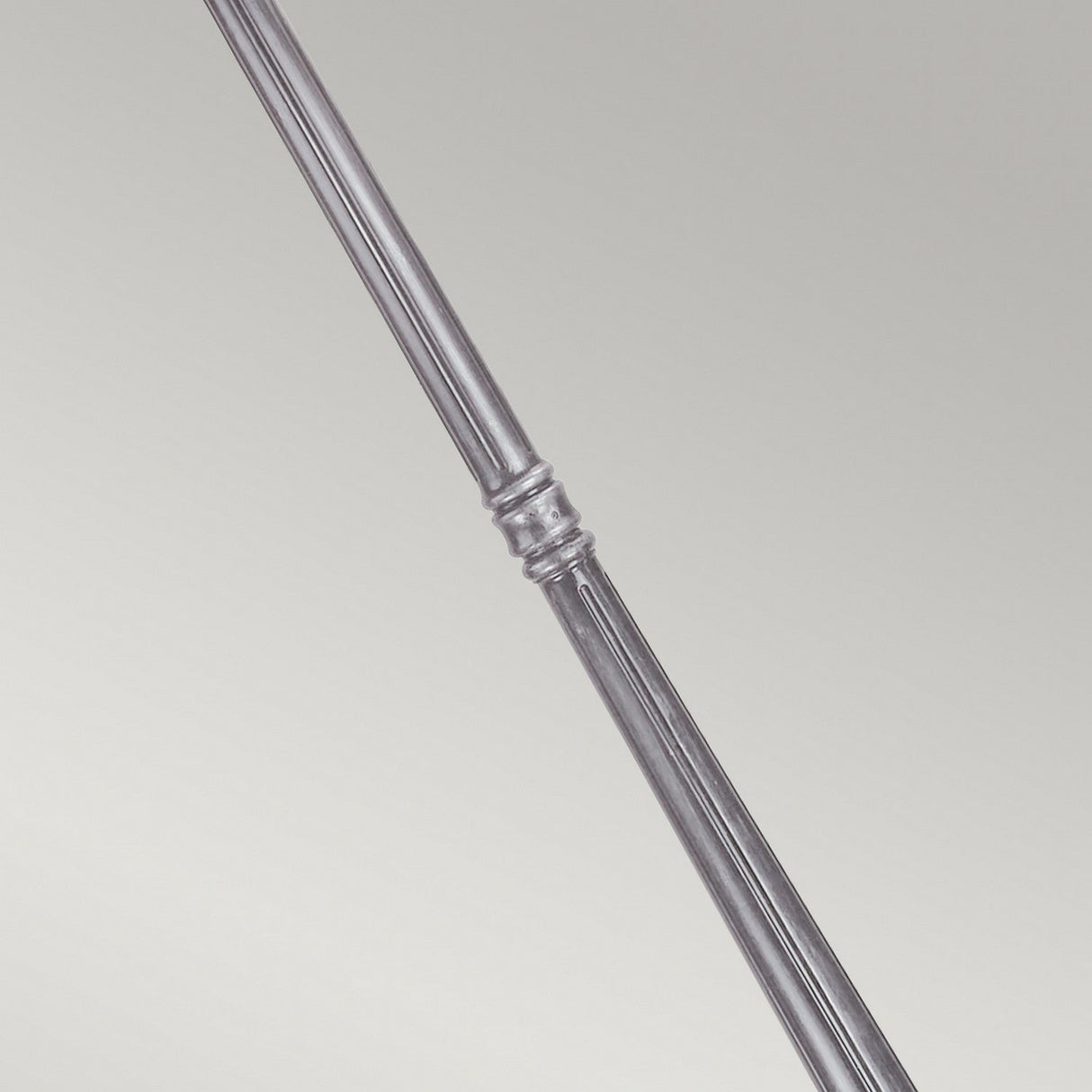 A close-up view of a polished metal rod reminiscent of the sophisticated design of the Wexford 2 Light Lamp Post - Black/Silver, featuring a decorative ring detail in the center, set against a plain light gray background. The rod's shiny surface is highly reflective.