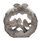 Round log resin figurine depicting three robins perched on a snowy branch, white and grey-brown tones with bark-textured edge and pinecone accents, on a plain white background.