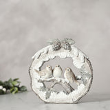 Round log resin figurine in white, featuring three robins perched on a snowy branch with pinecones and holly, set against a plain light grey background.