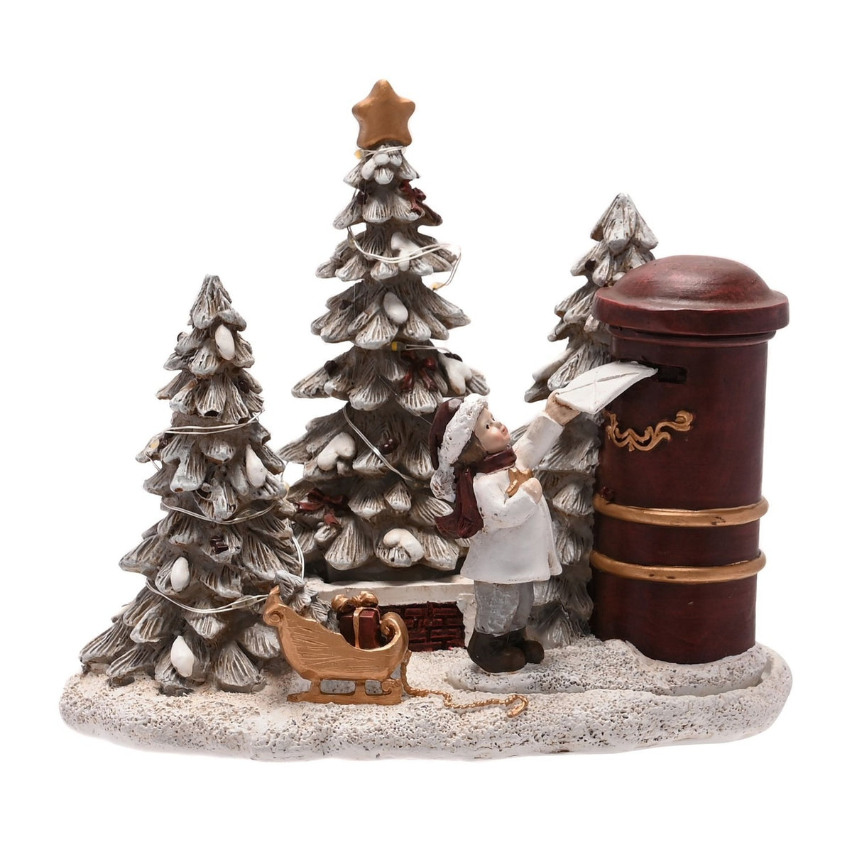 Light-up tree scene figurine of a boy in white coat and red hat posting a letter at a red pillar box, with frosted fir trees, gold star, and a gold sleigh of parcels on a snowy resin base.