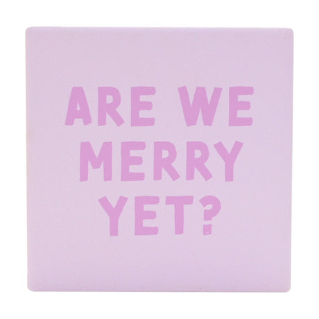 Square ceramic Christmas coaster in soft purple with "Are We Merry Yet?" printed in chunky orchid pink capitals, matt finish, shown on a plain white background.