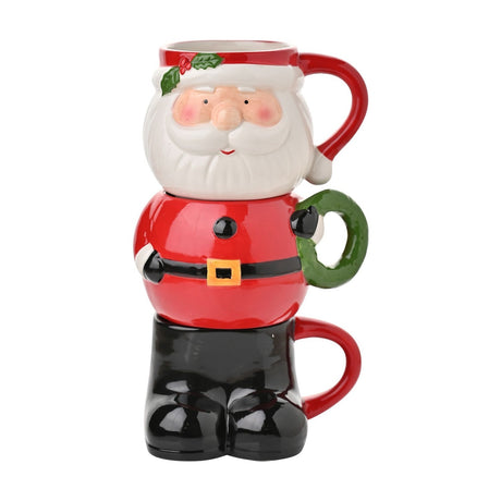 Set of 3 Christmas Santa stacking glazed stoneware mugs in red, forming his face with holly-trimmed hat, red jacket with black belt and buckle, and black boots, shown on a plain white background.