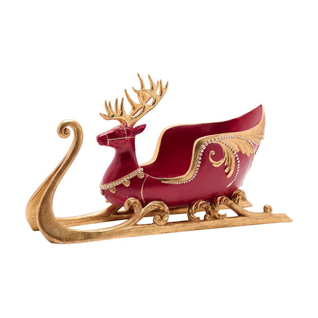 Deer and sleigh resin wine bottle holder in red with gold antlers, scrolled runners, and leaf-shaped flourishes with beaded trim, shown on a plain white background.