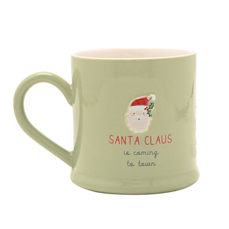 Green stoneware mug with embossed Santa Claus face, red hat and holly, printed "Santa Claus is coming to town" text, pink interior, on a white background.
