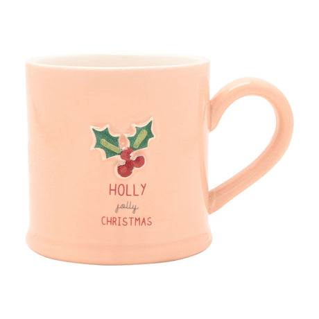 Pink stoneware mug with an embossed holly and berries sprig and "HOLLY jolly CHRISTMAS" text, C-shaped handle, shown on a plain white background.