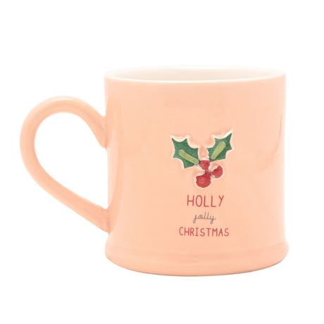 Pink stoneware mug with embossed holly and berries design and "HOLLY jolly CHRISTMAS" text, featuring a curved handle, shown on a white background.