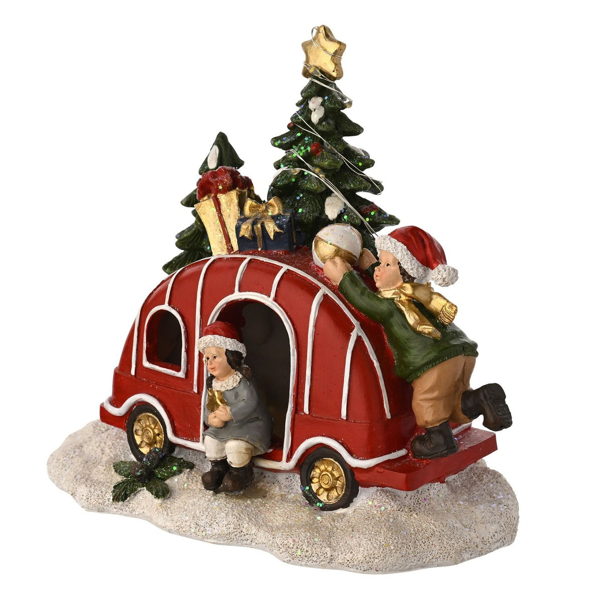 Christmas Caravan Plastic Light-Up Decoration in red with white trim and gold wheels, topped with gifts and trees, two Santa-hatted children figures, on a snowy base against a white background.