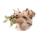 Straw squirrel ornament, 10.5 x 19.5cm, sitting upright holding a frosted pine cone and green leaf sprig, brown body, white belly, bushy tail, black eyes, on a white background.