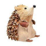 Straw hedgehog ornament with a tan bristle face, glossy black eyes and nose, brown pinecone-style glitter-edged spines, and clay feet, shown on a plain white background.