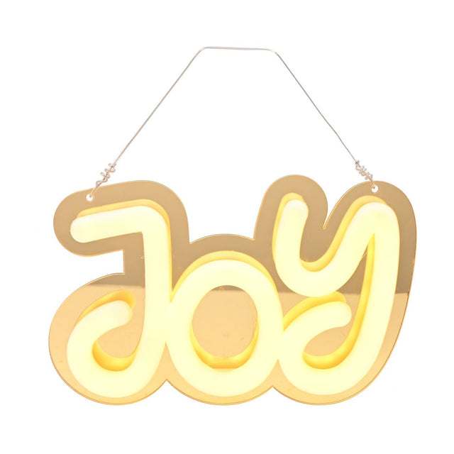 Gold mirrored plastic "Joy" LED neon hanging decoration with rounded white letters glowing warm yellow, hung on a thin cord against a plain white background.