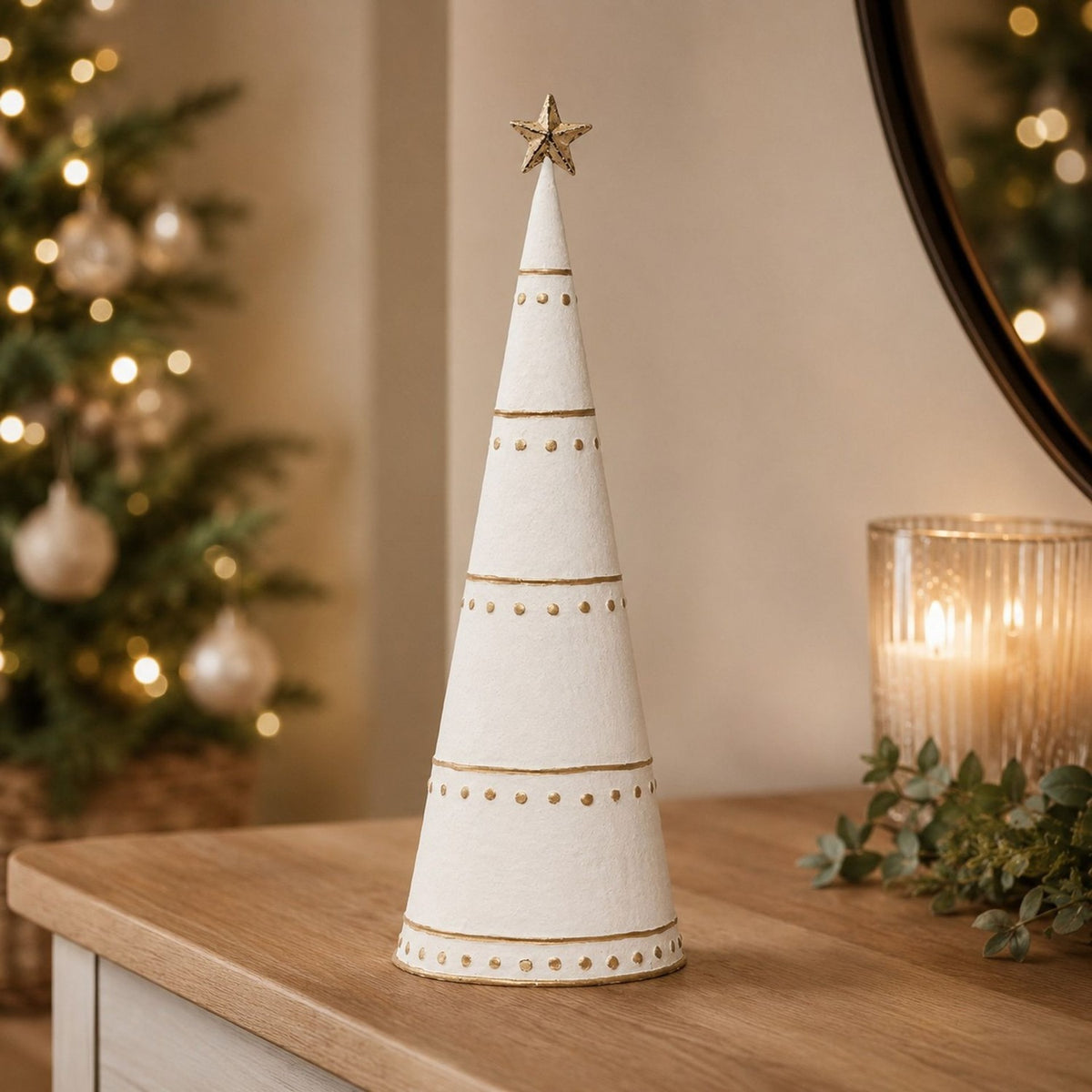 White metal cone Christmas tree ornament, 43cm, with gold bands, dots, and star topper, displayed on a wooden sideboard with candle and festive decor.