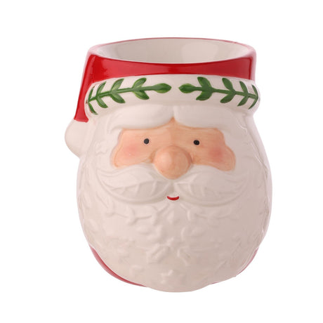 Ceramic wax melt burner shaped as Santa's face, with a red hat band, green leaf trim, rosy cheeks, and an embossed white beard, shown on a plain white background.