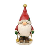 Skiing Santa Gonk resin tabletop Christmas decoration in red, with pointed hat, gold pompom, white textured brim, holly sprig, long white beard, and ski poles, on a plain white background.