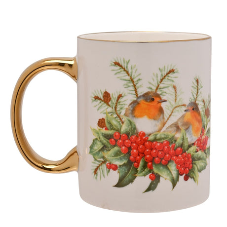White porcelain mug with gold rim and gold-plated handle, featuring a printed design of two robins among holly berries, leaves and pine sprigs, shown on a plain white background.