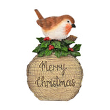 Merry Christmas Robin figurine with brown wings perched on a log, surrounded by holly leaves and red berries, "Merry Christmas" script on the log front, plain white background.