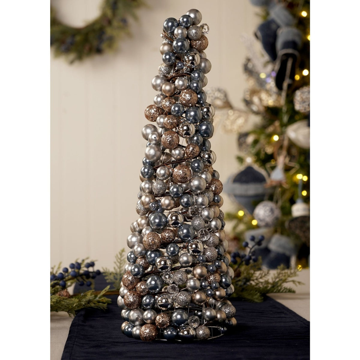 Cone-shaped Metal Ball Christmas Tree Decoration, 47.5cm, covered in clustered silver and gold baubles with crystal accents, displayed on a table with festive greenery in the background.
