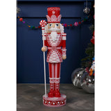 Giant 92cm resin Christmas nutcracker ornament in red and pink with white detailing, crown-band hat, white beard, candy-cane staff, standing on a round base indoors.