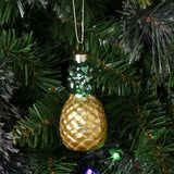 Glass pineapple Christmas bauble with yellow, gold-glitter lattice body and green glittered leaves, hanging by a gold cord on a Christmas tree.