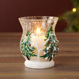 Crackle glass candle holder, 9.5cm, with hand-painted green pine trees, white snow detail and bauble accents, lit candle inside, set on a wooden surface.