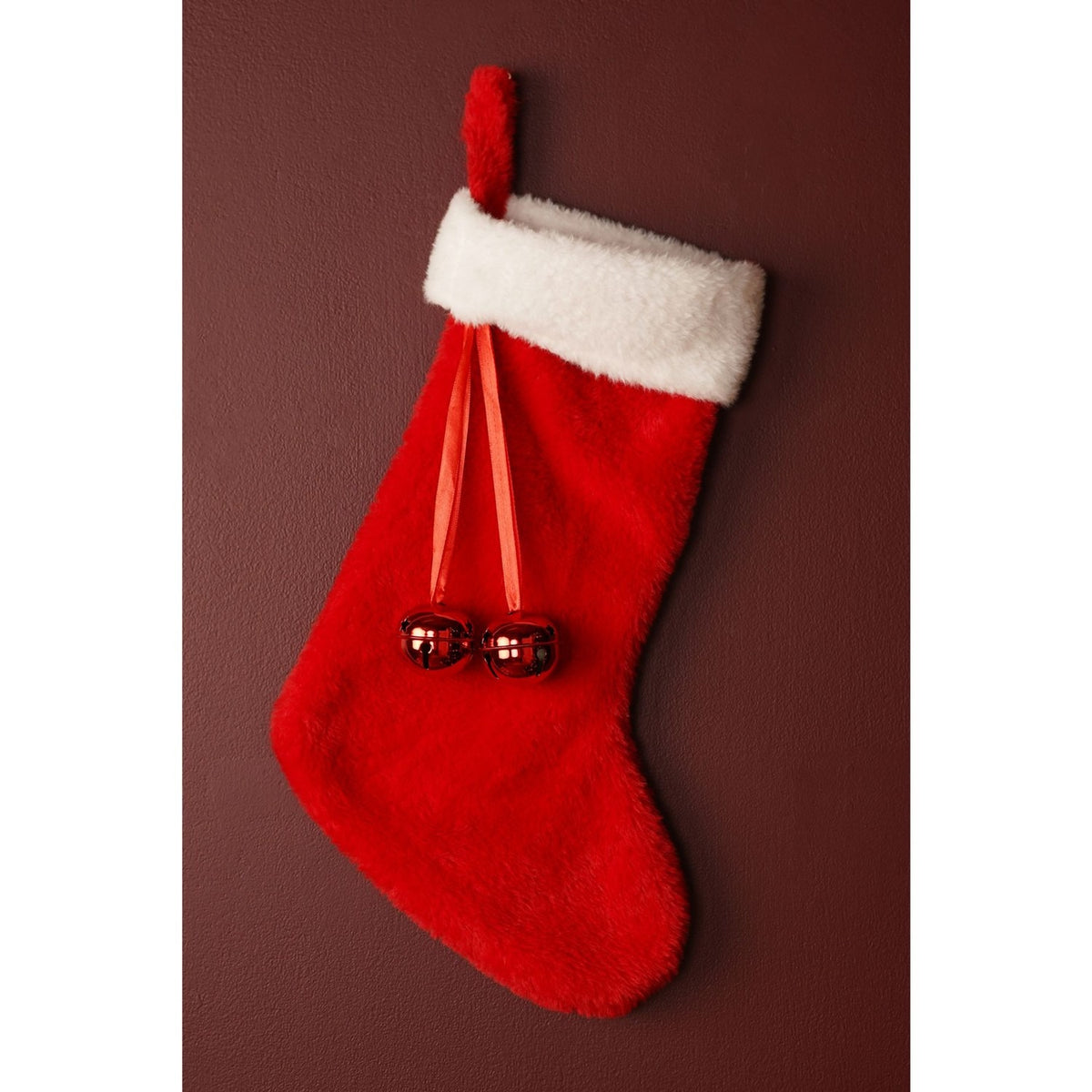 Red Christmas stocking, 44cm, with soft faux-fur body, folded white fluffy cuff, hanging loop, and two red jingle bells on ribbons, shown against a dark red background.