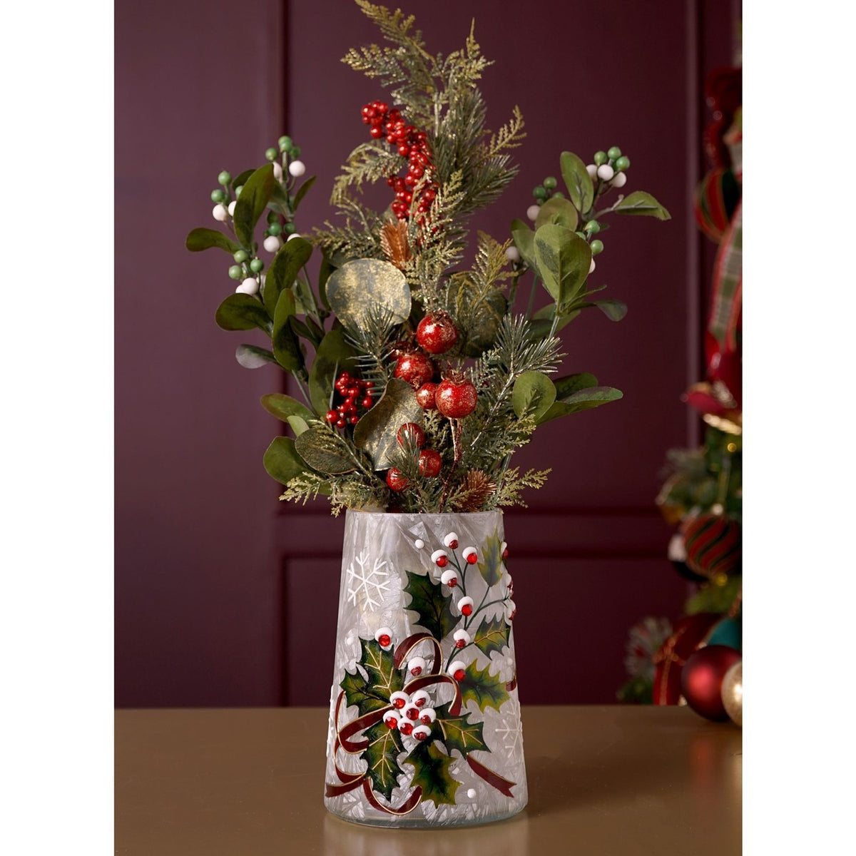White crackle glass vase, 18.2cm, frosted finish with painted holly leaves, red berries and ribbon, holding a festive greenery and red berry arrangement against a dark wall.