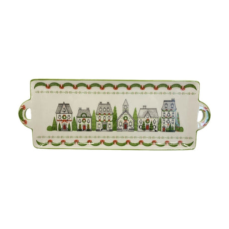 Rectangular cream earthenware cake plate with side handles, illustrated Christmas houses and church with wreaths, bordered by green garland and red bow patterns.