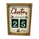 Wooden Christmas Countdown Plaque in a natural wood frame with cream textured panel, red "Christmas" script, holly details, and two green number tiles reading "25 days," on a plain white background.