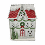 Frosted LED House light-up Christmas decoration, white plastic townhouse with red scalloped roof, glittering snow, green garlands, wreath and trees, on a plain white background.