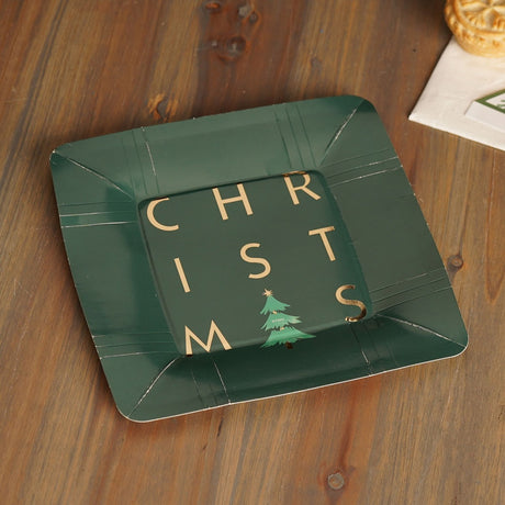 Square green paper plate with "CHRISTMAS" hot-stamped in gold foil and a small Christmas tree, gold line details on the rim, shown on a wooden table.
