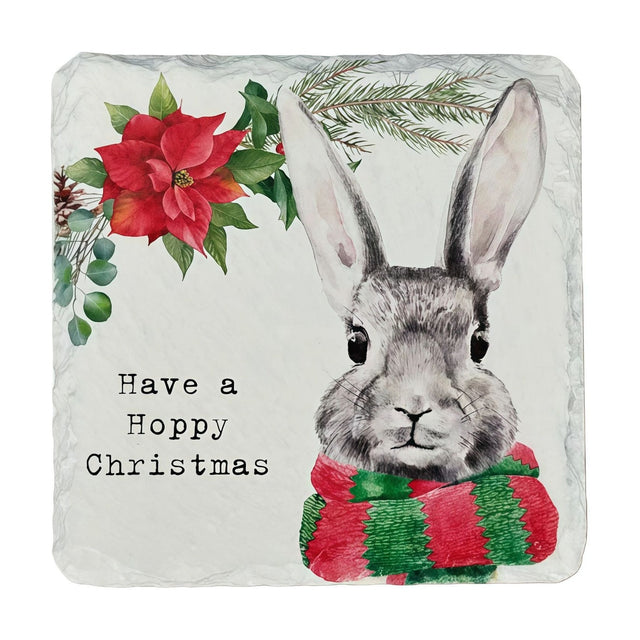 Square slate coaster featuring a grey rabbit in a red and green striped scarf beside a red poinsettia and pine sprig, with "Have a Hoppy Christmas" text on a white background.
