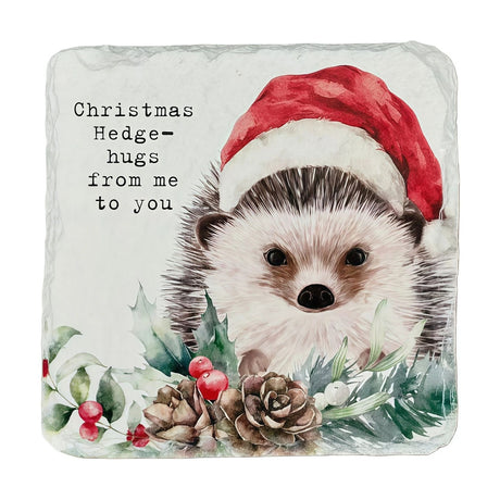 Square slate coaster with a hedgehog in a red Santa hat amid holly, berries and pine cones, with "Christmas Hedge-hugs from me to you" text on a white background.
