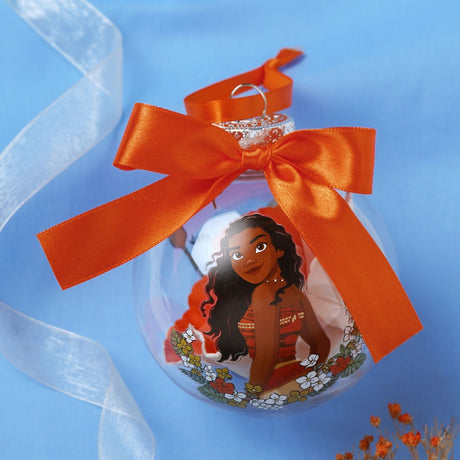 Clear round Christmas bauble printed with Princess Moana among orange and white flowers, filled with faux blooms and topped with an orange satin bow, on a blue background.