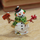 Handpainted white metal snowman trinket box with hinged lid, black top hat, green scarf and ear muffs, holding a "Merry Christmas" sign and candy cane.