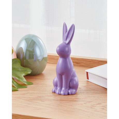 Yaypan Ceramic Rabbit Ornament in lilac, sitting upright with tall ears and a glossy finish, displayed on a wooden shelf beside a decorative egg and plant.