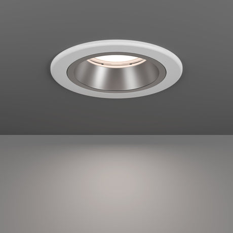 Yebra LED Downlight in white, a round recessed ceiling fixture with a white plastic body and deep-set silver reflector, shown glowing warm white above a plain grey background.