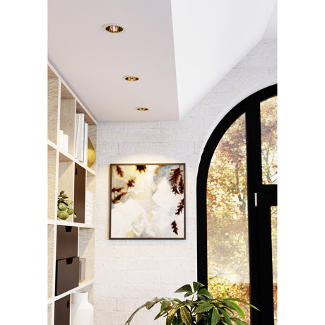 Three round Yebra Smart LED downlights with white bezels and gold reflector cups fitted into a white ceiling above a bookshelf and arched window.